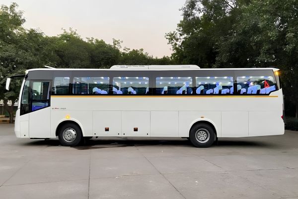 White luxury bus parked in an open area, side view designed for large group transportation.