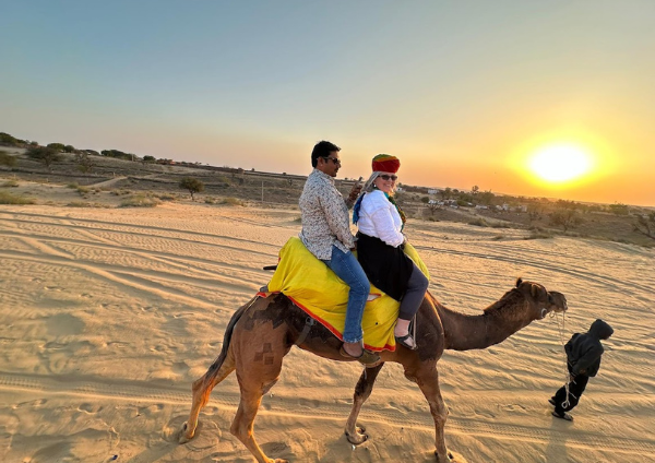A tourist enjoying a camel ride safari in the golden sands near Jodhpur Bishnoi Village Safari Jodhpur.