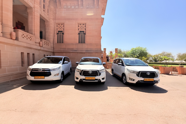 White Toyota Innova Crysta SUVs parked outside Umaid Bhawan Palace, providing premium taxi and outstation cab services in Jodhpur for families, tourists, and corporate travelers.