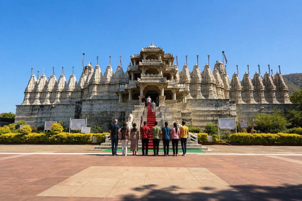 Ranakpur Jain Temple in Rajasthan showcasing its magnificent white marble architecture with visitors walking toward the grand entrance under a clear blue sky.